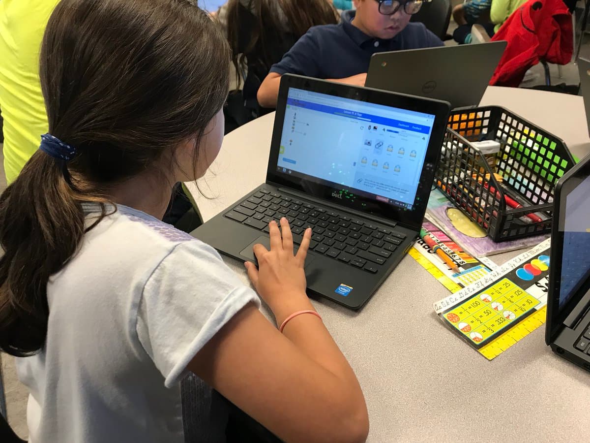 A student working through a Codemoji lesson on her laptop